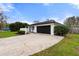 Single-story home featuring a black garage door, lush green lawn, and manicured shrubbery at 2326 Eastmeadows Rd, Lakeland, FL 33812