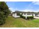 A charming single-story home with a black garage door, lush green lawn, and manicured shrubbery at 2326 Eastmeadows Rd, Lakeland, FL 33812