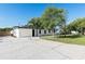 A well-maintained single-story home featuring a spacious driveway, a well manicured lawn and mature trees at 2521 Coral Way, Lakeland, FL 33801