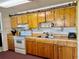 Functional kitchen featuring ample wood cabinets, a white range, and a stainless steel sink at 3023 Maplewood Ave, Lakeland, FL 33803