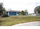 Side view of a blue single-story home surrounded by a spacious yard, with a palm tree and a long driveway at 304 Olmo Ct, Winter Haven, FL 33880