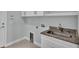 Well-lit laundry room featuring a utility sink, granite countertop, and white cabinets with chrome pulls at 3224 Pearly Dr, Lakeland, FL 33812