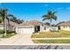 Inviting single-story home with a two car garage, lush green lawn, and mature palm trees at 3882 Rollingsford Cir, Lakeland, FL 33810