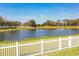 Scenic view of a pond with a white picket fence in the foreground and trees lining the background at 3882 Rollingsford Cir, Lakeland, FL 33810