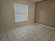 Empty bedroom with light tan walls, tile floors, and window at 406 Fox Lake Dr, Lakeland, FL 33809