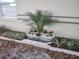 Landscaping featuring a metal planter with a palm tree, flowers and decorative rock at 406 Fox Lake Dr, Lakeland, FL 33809