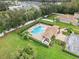 Aerial view of community pool with lounge area, palm trees, and a parking area surrounded by green spaces at 4688 Hickory Stream Ln, Mulberry, FL 33860