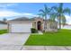 Charming single-story home featuring a well-maintained lawn, two palm trees, and a welcoming red front door at 4688 Hickory Stream Ln, Mulberry, FL 33860