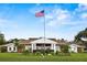 A grand community clubhouse under the American flag with beautifully landscaped gardens at 4911 Colonnades Club Blvd, Lakeland, FL 33811