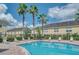 Community pool with clear blue water, lounge chairs, palm trees, and a sunny sky at 5377 Quarry Rock Rd, Lakeland, FL 33809