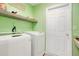 Bright laundry room featuring a washer and dryer, a grey shelf and a six panel door at 554 Lorient Dr, Eagle Lake, FL 33839