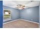 Bedroom with neutral carpet, blue walls, ceiling fan, and large window at 560 Hatchwood Dr, Haines City, FL 33844