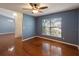 Living room features hardwood floors, blue walls, ceiling fan, and a large window at 560 Hatchwood Dr, Haines City, FL 33844