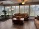 Comfortable sunroom featuring a plush brown sofa, wood flooring, and a sun-drenched view through window blinds at 5982 Crane Dr, Lakeland, FL 33809