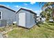 Shed on grass covered lot has painted grey siding and white door at 6792 Brentwood Ne Dr, Winter Haven, FL 33881