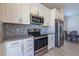 Modern kitchen with white cabinets, stainless steel appliances, and mosaic backsplash at 685 Meadow Pointe Dr, Haines City, FL 33844