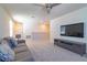 Cozy upstairs living room featuring plush carpeting, a comfortable gray sofa, and a ceiling fan for added comfort at 685 Meadow Pointe Dr, Haines City, FL 33844