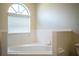 Bright bathroom with a tile-lined tub next to a window and white walls at 7997 Kaitlin Cir, Lakeland, FL 33810