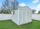 Light blue storage shed with double doors sits on the grassy lawn behind the house at 8350 Split Creek Cir, Lakeland, FL 33809