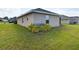 View of the backyard showing green grass, a neutral home exterior and green bushes at 1134 Legatto Loop, Dundee, FL 33838