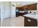 Well-lit kitchen featuring black appliances, dark wood cabinets, tile flooring and breakfast bar at 1134 Legatto Loop, Dundee, FL 33838