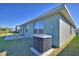 Rear exterior view of a home, featuring an AC unit, grassy yard, and a glimpse of the neighborhood at 136 Krenson Bay Loop, Winter Haven, FL 33881
