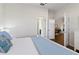 Bright bedroom with open doors to bathroom and office, light blue comforter and white walls at 1420 Mickelson Ct, Davenport, FL 33896