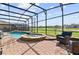Outdoor screened-in pool area with a spa, beautiful landscaping, and views of the green golf course at 1420 Mickelson Ct, Davenport, FL 33896