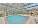 Lovely screened-in pool and patio area featuring a refreshing pool, spa, outdoor seating, and lush landscaping at 159 Coventry Cir, Haines City, FL 33844