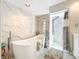 Modern bath featuring a soaking tub, marble tile, glass block accents, shower, and decorative rug at 21 Townhill Dr, Eustis, FL 32726