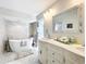 Spa-like bathroom with marble tile, a soaking tub, shower, and dual sink vanity with ornate accents at 21 Townhill Dr, Eustis, FL 32726