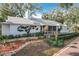 Charming one-story home with white exterior, front porch, mature trees, and lush landscaping at 21 Townhill Dr, Eustis, FL 32726