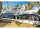 Side angle of the house with a sunroom addition, grass, and a large tree at 21 Townhill Dr, Eustis, FL 32726