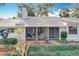 Charming one-story home with white exterior, front porch, mature trees, and lush landscaping at 21 Townhill Dr, Eustis, FL 32726