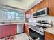 Modern kitchen boasts stainless steel appliances, granite countertops, and wood cabinets with backyard views at 21 Townhill Dr, Eustis, FL 32726