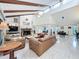 Spacious living room with vaulted ceilings, exposed wood beams, a stone fireplace, and tile flooring at 21 Townhill Dr, Eustis, FL 32726