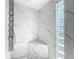 Luxurious walk-in shower with marble-patterned tile, multiple shower heads, a bench and privacy glass blocks at 21 Townhill Dr, Eustis, FL 32726