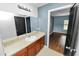 Bathroom features a vanity with solid surface countertop, wood cabinets, large mirror, and access to the bedroom at 2443 Torrens Dr, Lakeland, FL 33805