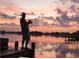 Sunset view of a person fishing on a dock, showcasing the peaceful lakeside lifestyle at 2820 Attwater Loop, Winter Haven, FL 33884