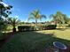 Beautiful back yard featuring lush green grass, tropical palm trees, and views of the water fountain at 394 Nolane Ln, Polk City, FL 33868