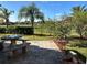 Backyard patio featuring a stone table and benches, landscaping, and lawn at 394 Nolane Ln, Polk City, FL 33868