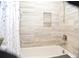Bathtub and shower combo featuring decorative tile, rainfall shower head, and recessed shelving at 3976 Cypress W Lndg, Winter Haven, FL 33884