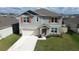 Two-story home with stone accents, two-car garage, well-manicured lawn, and neutral colored facade at 421 Chayne Pl, St Cloud, FL 34771