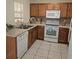 Functional kitchen featuring wood cabinets, white appliances, and tile flooring perfect for everyday cooking at 5407 Quarry Rock Rd, Lakeland, FL 33809