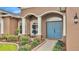 Inviting front entrance with blue double doors, surrounded by lush landscaping and charming decor at 6987 Heatherbrook Dr, Lakeland, FL 33809