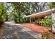 View of covered carport with brick flooring surrounded by lush landscaping and a driveway at 810 Orange Park Ave, Lakeland, FL 33801