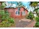 Back exterior view of home, featuring lush landscaping, windows, and brick-lined walkway at 810 Orange Park Ave, Lakeland, FL 33801