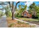 View of a quaint single-story house with a lush green yard, mature tree, and brick lined street at 810 Orange Park Ave, Lakeland, FL 33801