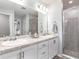 Bathroom featuring double vanity with granite countertop, white cabinets, large mirror, and glass-enclosed shower at 1001 Aruba Ave, Mulberry, FL 33860