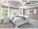 Spacious main bedroom featuring a decorative white headboard, tray ceiling, and natural light from multiple windows at 1001 Aruba Ave, Mulberry, FL 33860